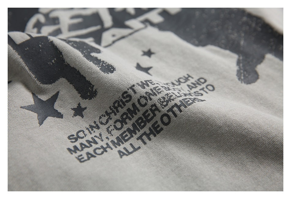 Angled close-up of the gray T-shirt’s dark printed stars, figures and English text.