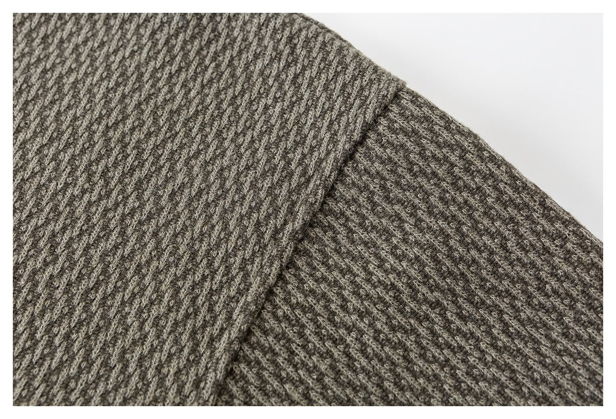 Close-up of gray-brown ribbed knit fabric with a folded overlapping edge.