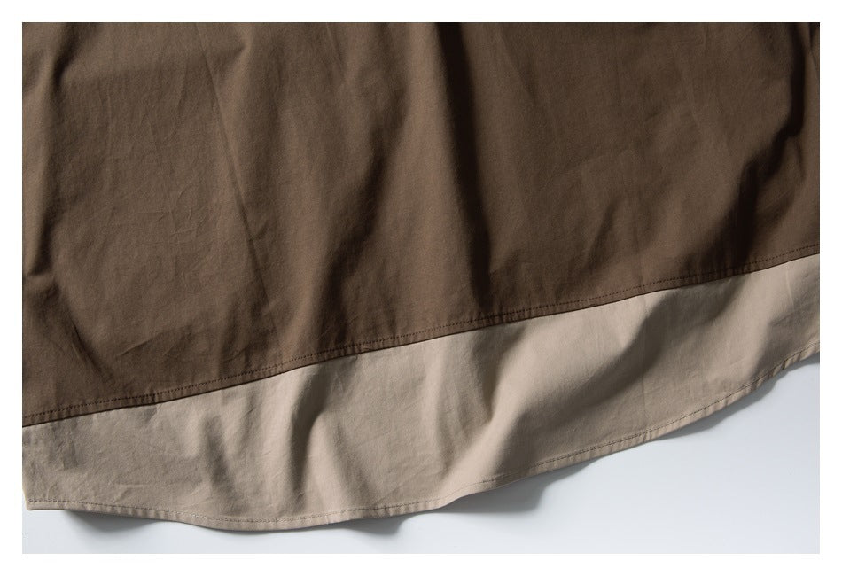 Close-up of the curved hem with a light beige color-blocked panel beneath brown fabric.