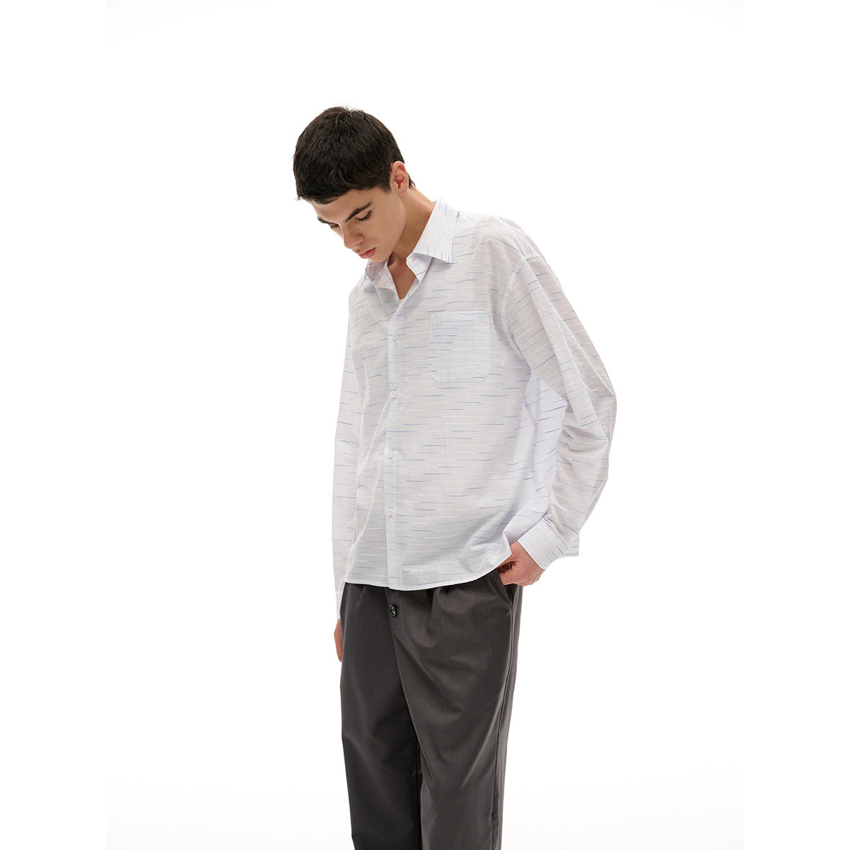 Model in a white button-up shirt with fine blue-gray horizontal dashes and a chest pocket, shown at a three-quarter angle.