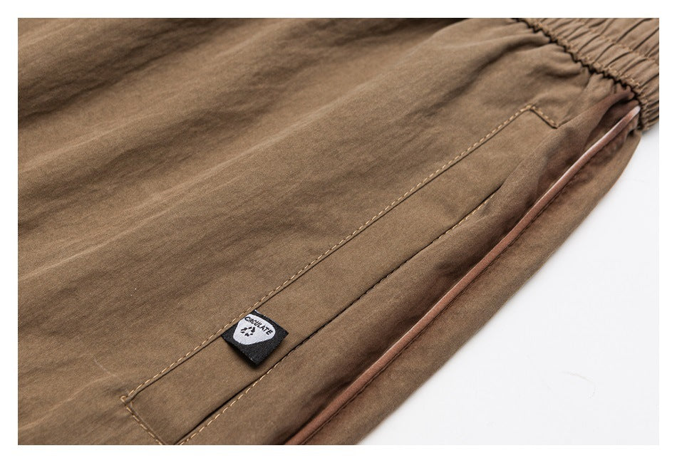 Close-up of a tan pants pocket, fabric, edge piping, and a small sewn label.