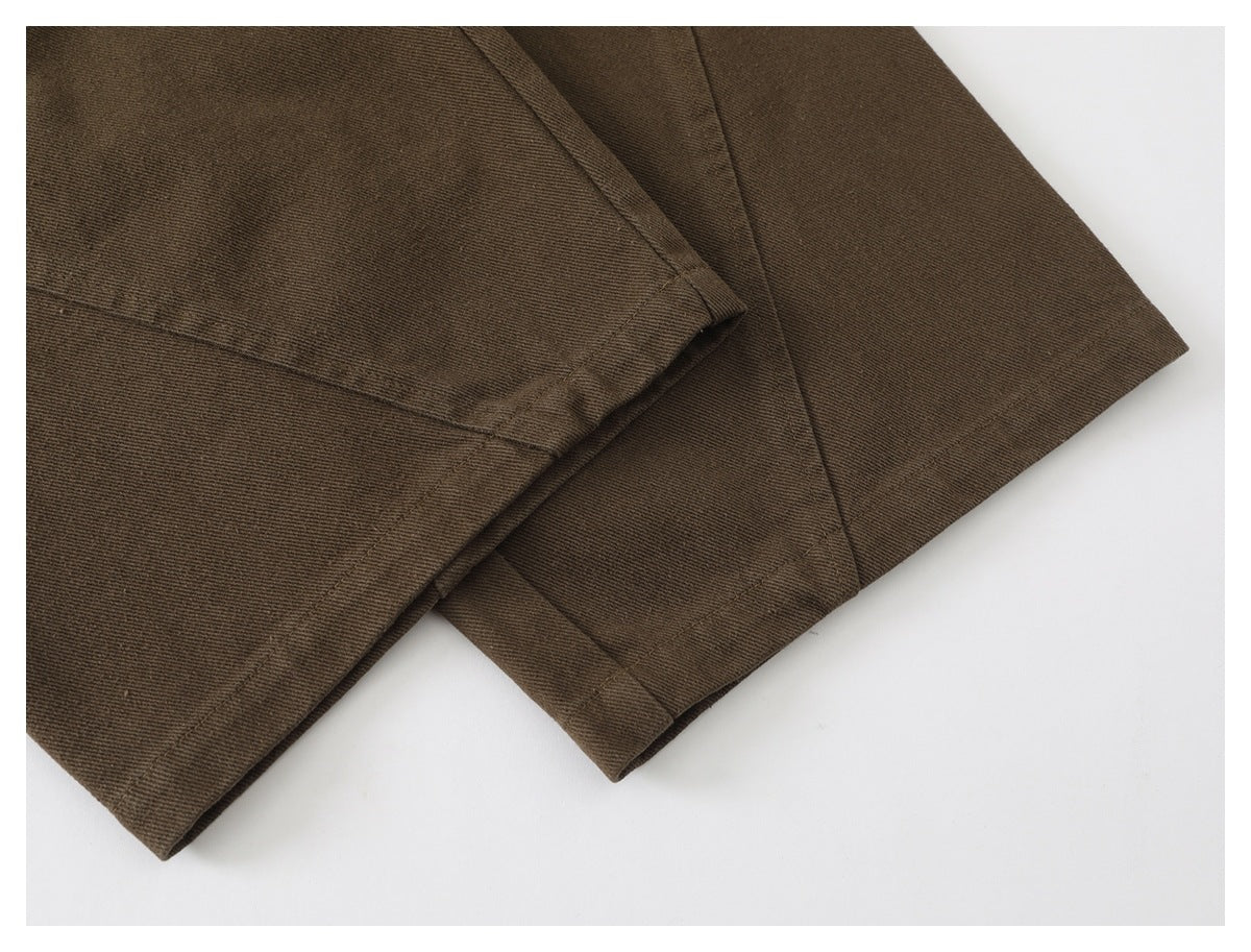Close-up of the stitched hems on brown trouser legs.
