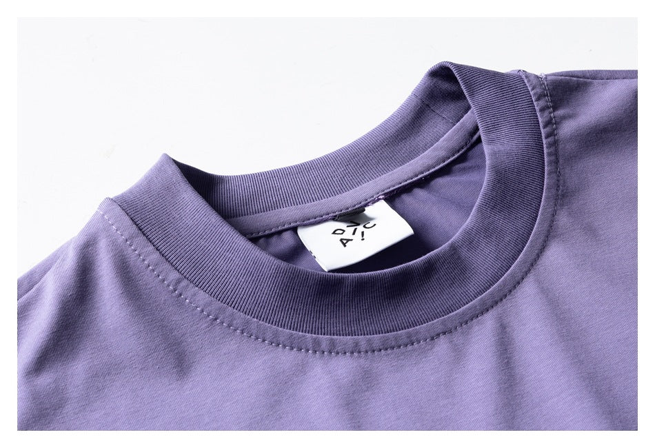 Close-up of a purple T-shirt's ribbed crew neck, stitching, and inner label.