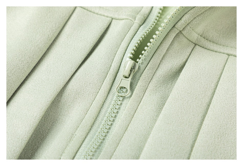 Close-up of a pale sage-green garment's front zipper and surrounding seams.
