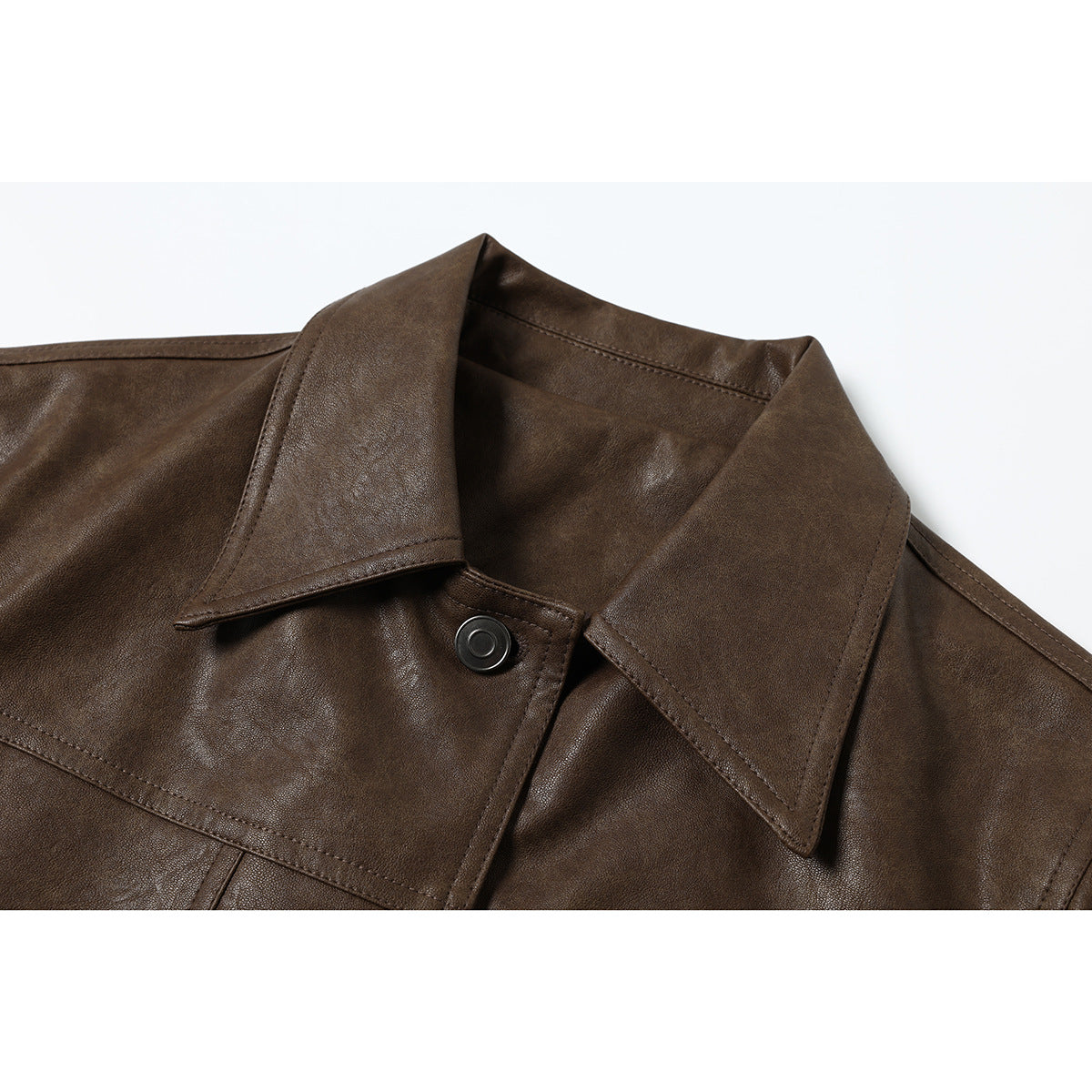 Close-up of a dark brown jacket's wide pointed collar, stitching, and round metal snap.