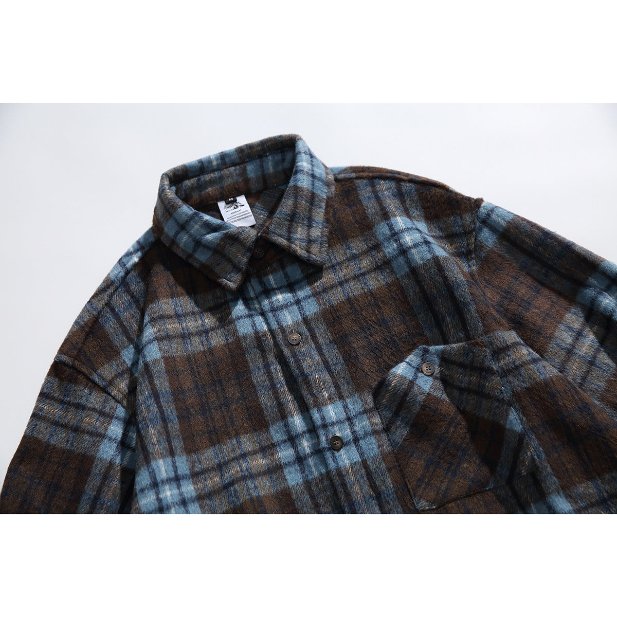 Close-up of a blue and brown plaid shirt front with pointed collar, buttons, and chest pocket.