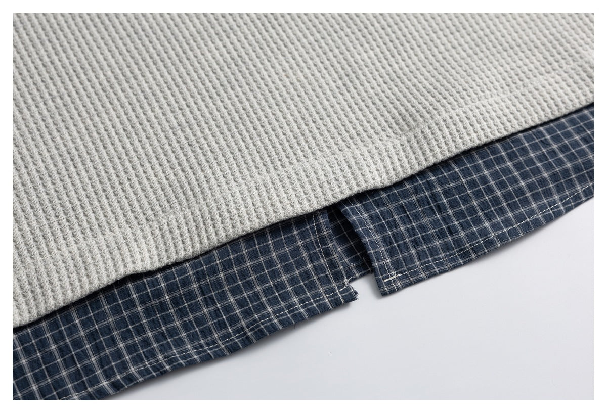 Close-up of a light gray knit hem layered over a navy plaid fabric hem.