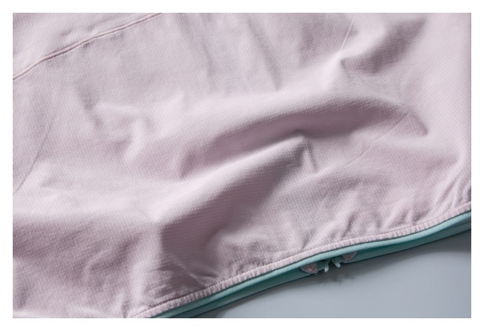 Close-up of the pale pink garment's perforated fabric, hem seam, and mint-green trim.