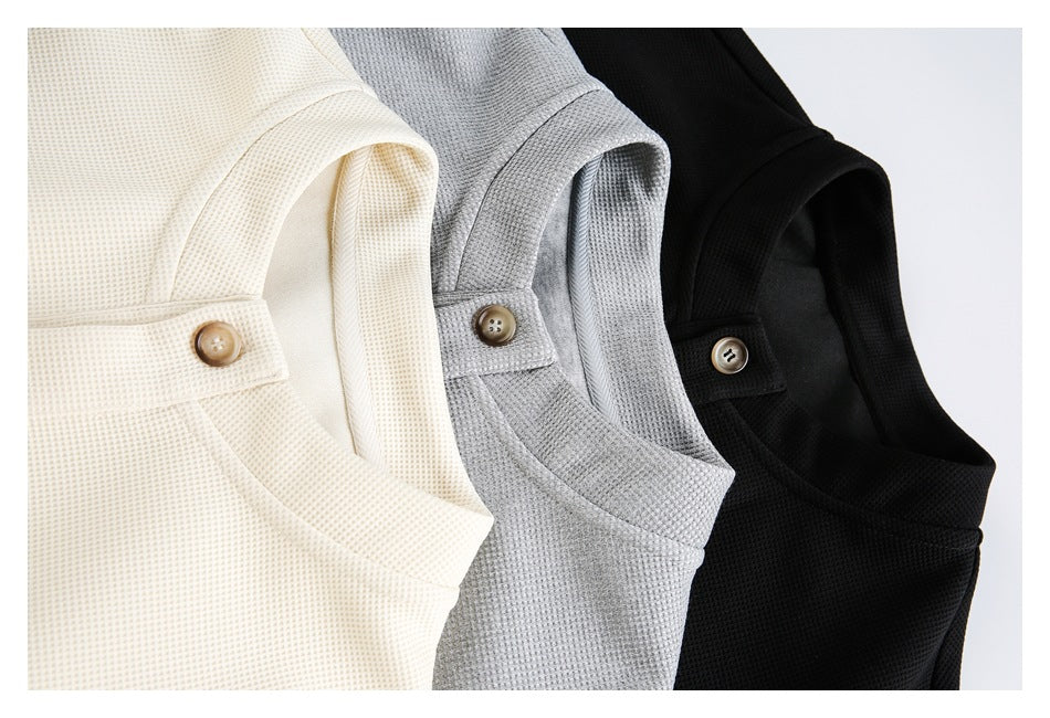 Three textured knit tops in cream, gray, and black, arranged together to show their necklines and buttons.