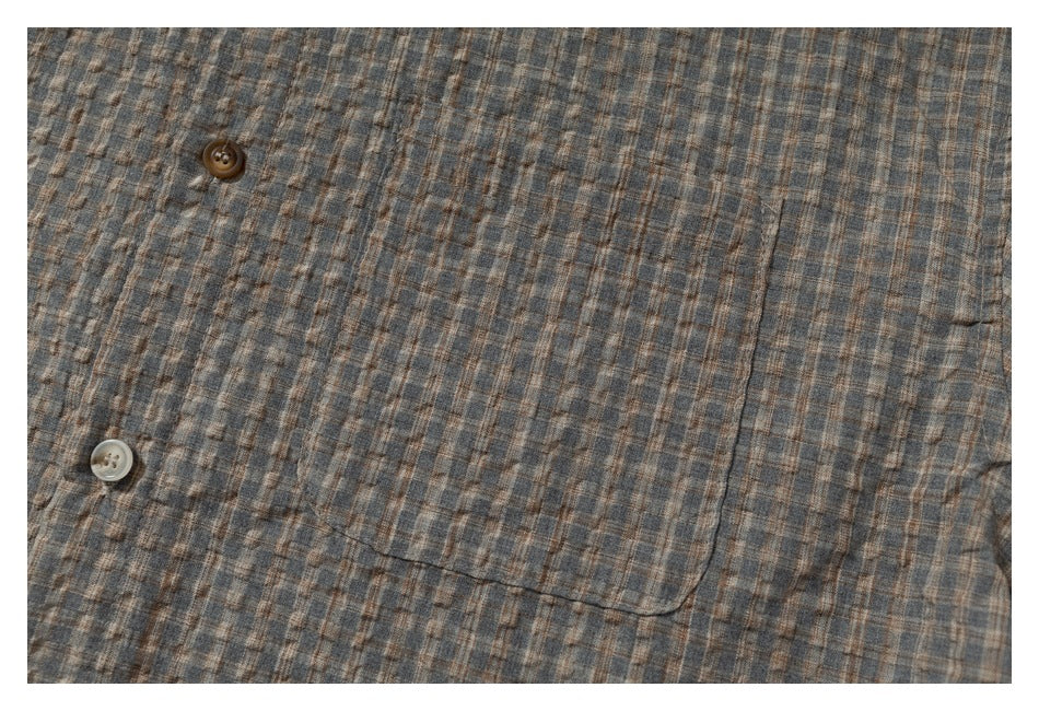 Framed close-up of a gray-brown plaid shirt's chest pocket and buttons.