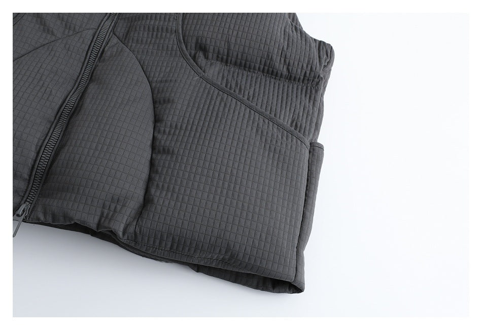 Close-up of the charcoal vest's quilted lower side panel, curved seams, and hem.