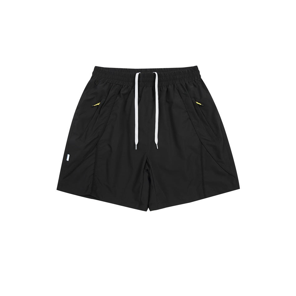 Black athletic shorts flat lay with white drawstring, elastic waist and diagonal side pockets with yellow zip pulls