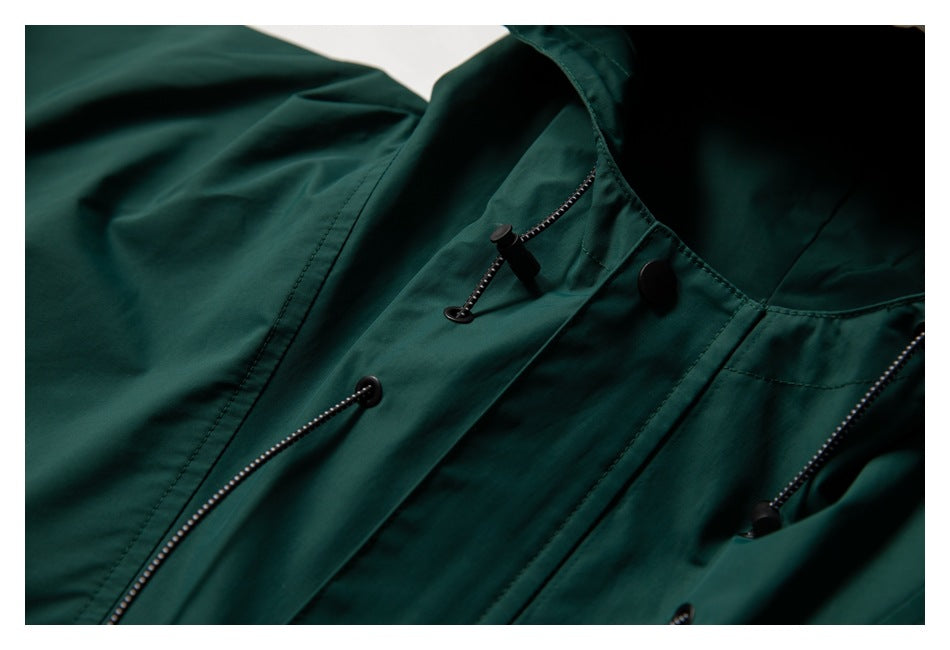 Close-up of the dark teal jacket's front placket, showing snap closure and adjustable drawcords.