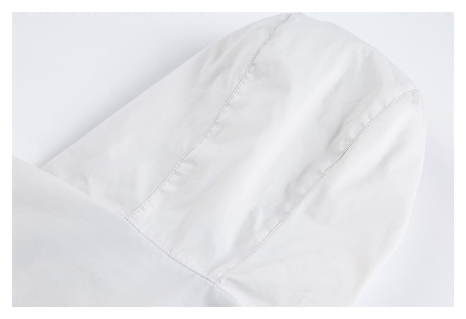 Close-up of a white garment showing curved panel seams and fine stitching.