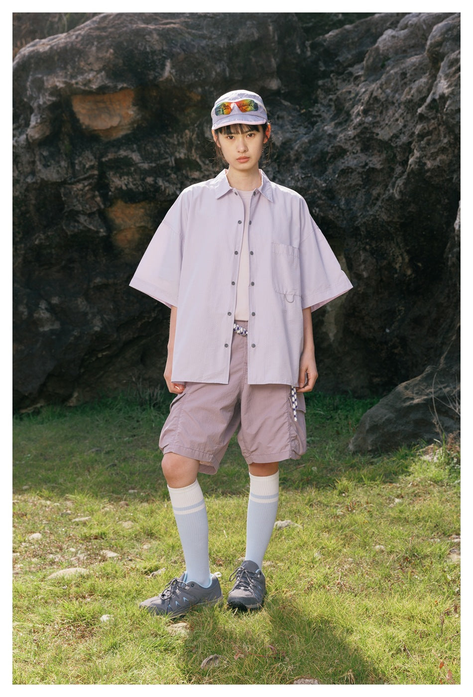 A woman models a pale lavender short-sleeve button-up shirt and matching cargo shorts outdoors.