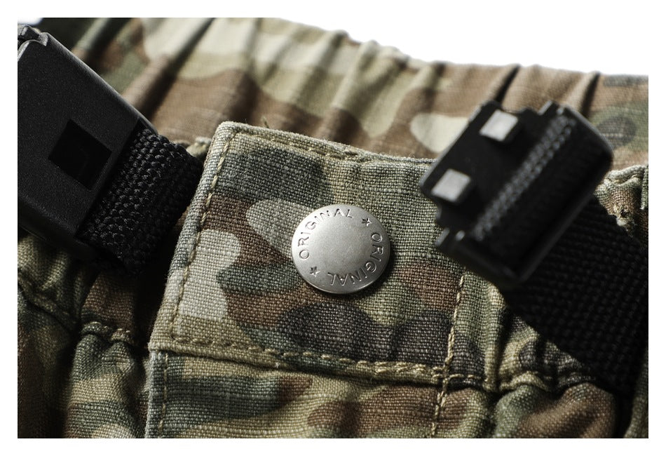 Close-up of a metal waistband button and black belt hardware on camouflage pants.