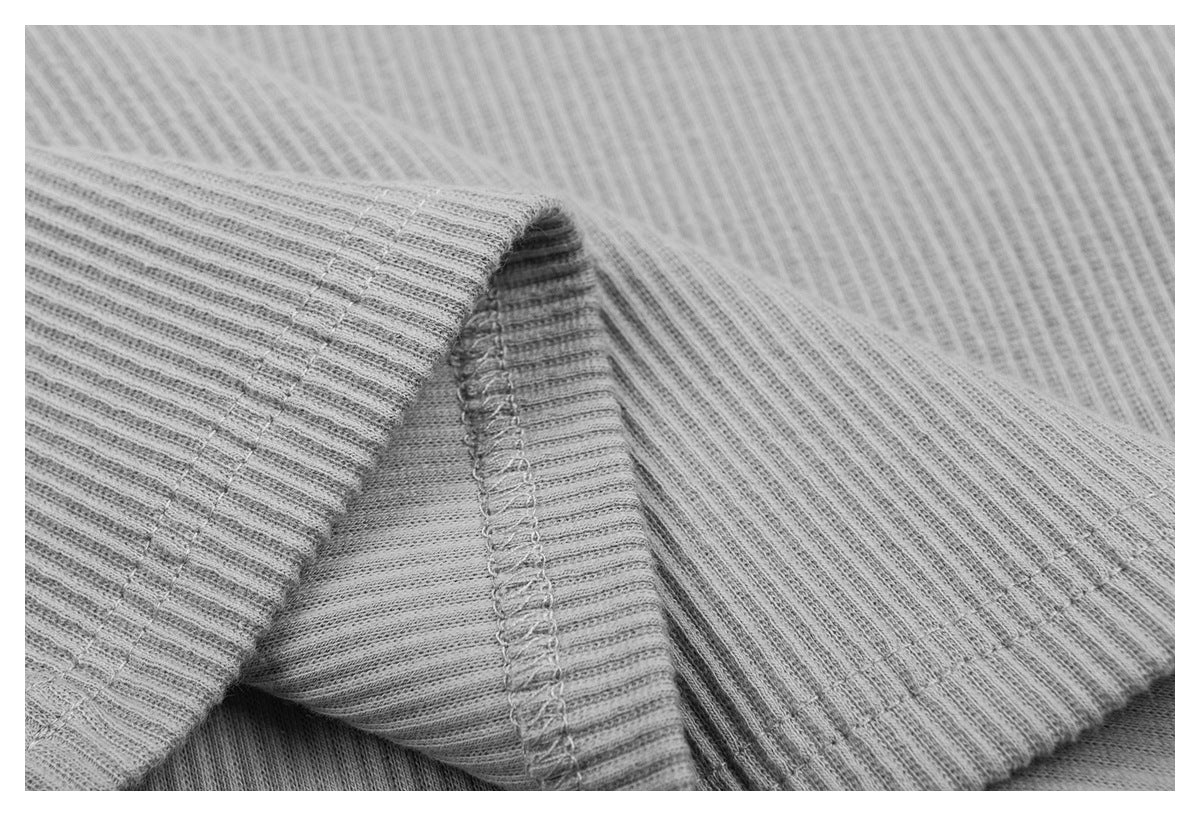 Macro view of ribbed fabric folds and an overlocked seam on the light gray top.