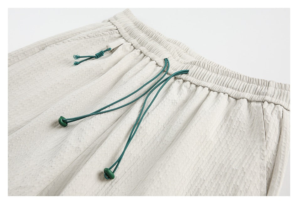 Close view of white textured shorts with a gathered waistband and teal drawcords.