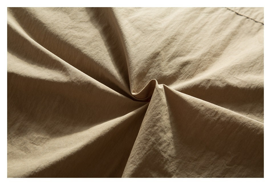 Extreme close-up of the tan jacket fabric gathered into a central fold.