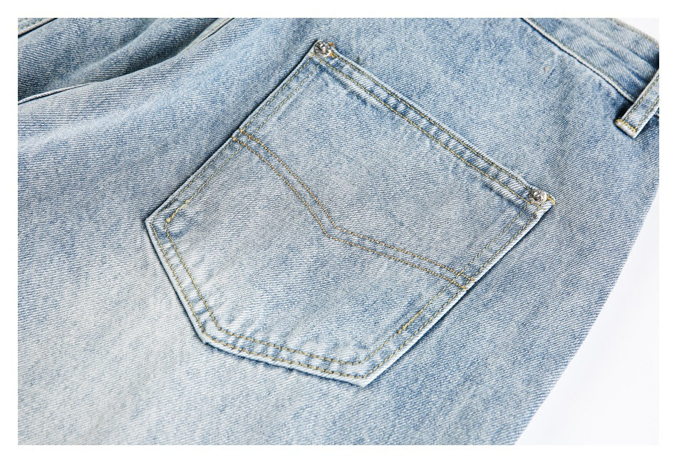 Close-up of a light-wash denim jeans pocket with contrast stitching and metal rivets.
