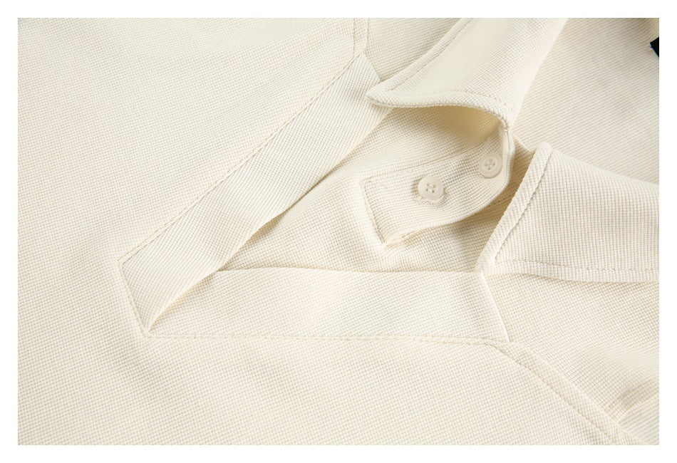 Close-up of the cream garment's collar and short button placket with two matching buttons.
