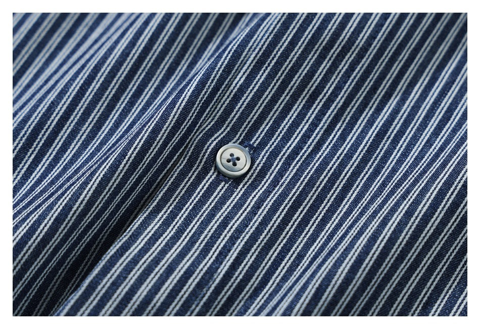 Close-up of a gray button on dark blue fabric with narrow white stripes.