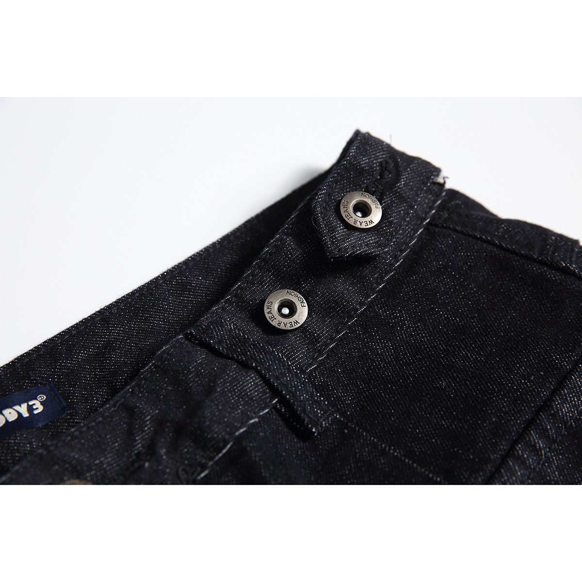Close-up of two metal buttons on the waistband of black denim trousers.