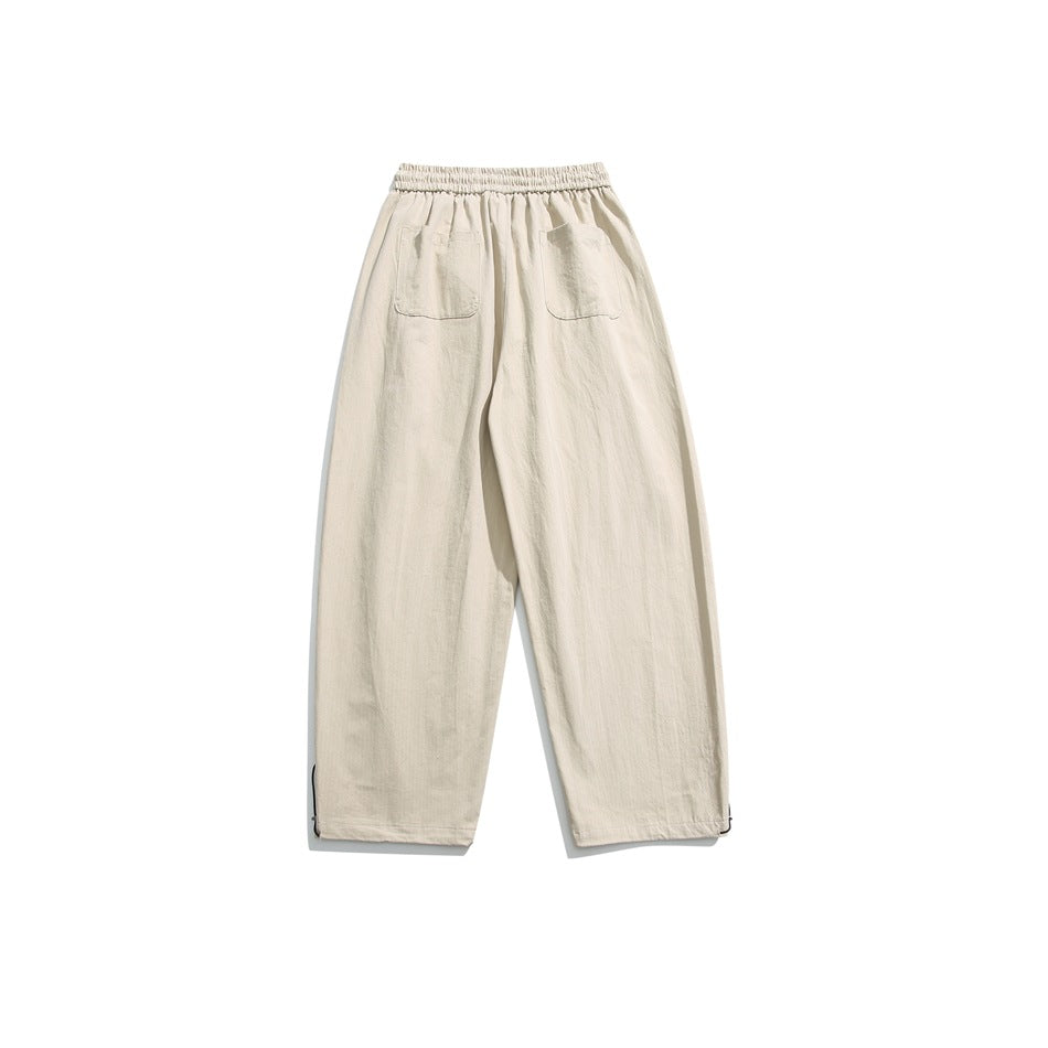 Back view of off-white wide-leg trousers with an elastic waist, two patch pockets, and adjustable ankle cords.