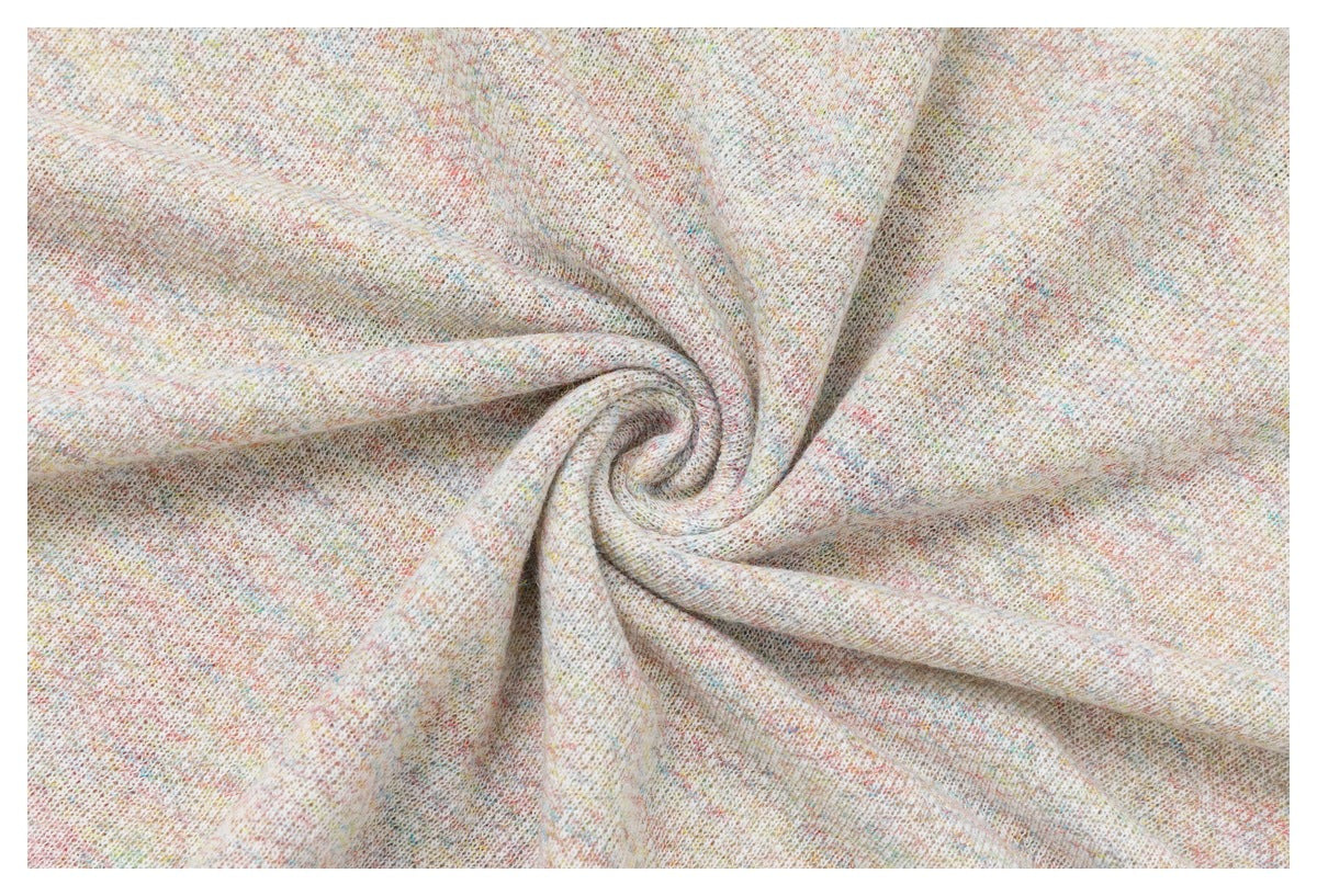Close-up of pale cream knit fabric with subtle multicolored flecks, gathered into a spiral.