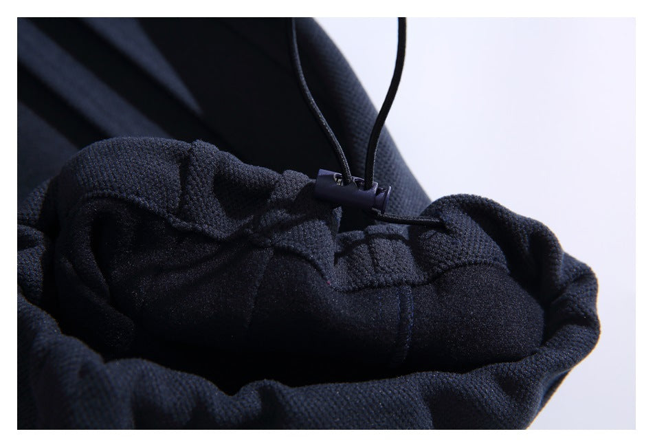 Close-up of the inside of dark pants showing a gathered edge and an adjustable cord with a stopper.