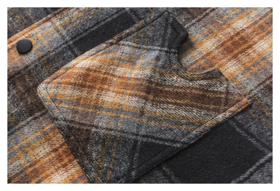 Close-up of a flap pocket and black button on a charcoal, gray, cream, and rust plaid garment.
