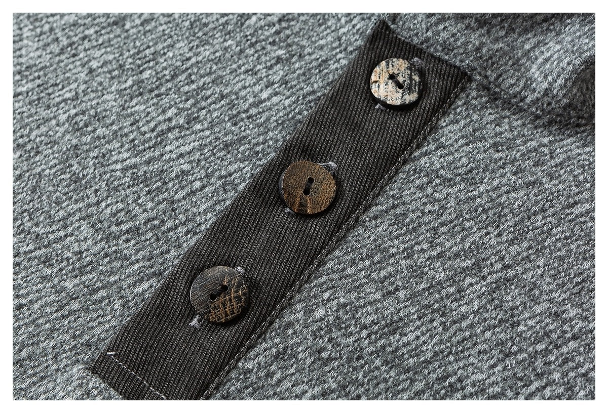 Close-up of three mottled brown buttons on a dark ribbed placket against gray textured fabric.