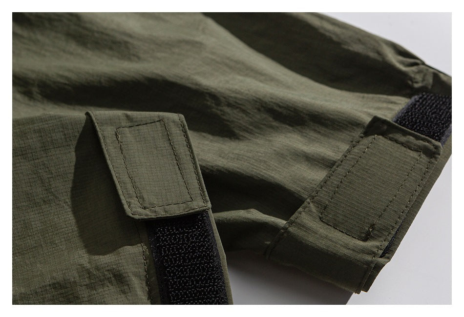 Close-up of an olive garment with two adjustable hook-and-loop fastening tabs.