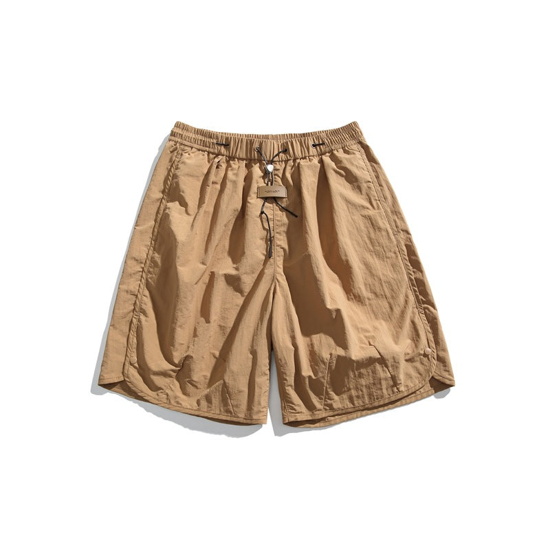 Tan brown loose shorts with elastic drawcord waist, front tag and curved snap side hems, flat lay