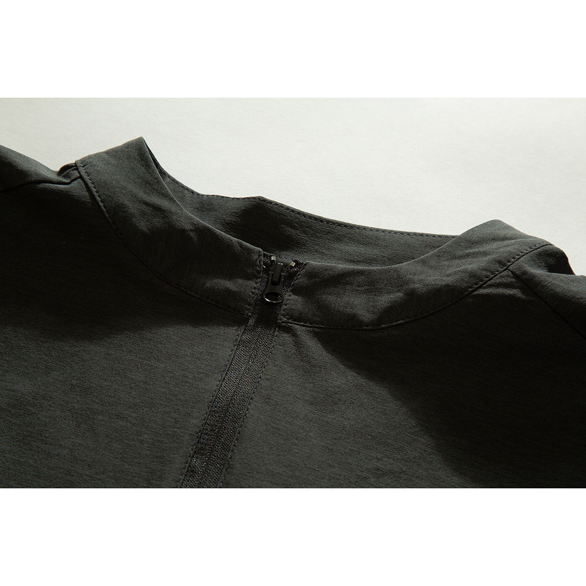 Close-up of a charcoal short stand collar and quarter zipper on a short-sleeve shirt.