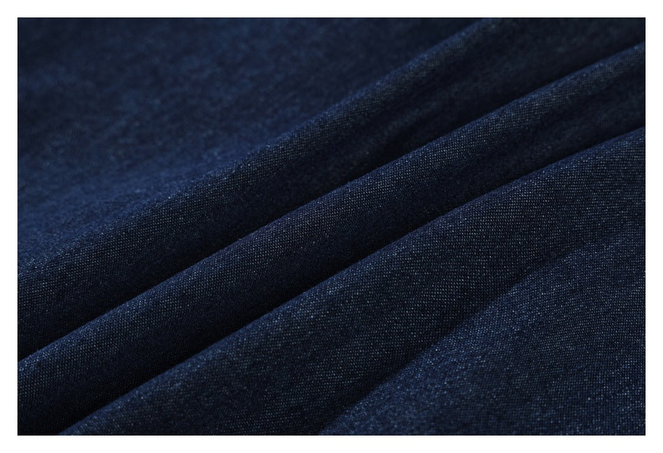 Macro view of dark indigo denim fabric arranged in soft folds.