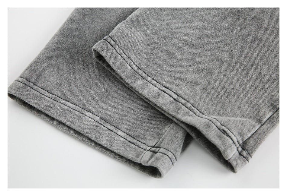 Close-up of the double-stitched hems on gray sweatpant legs.
