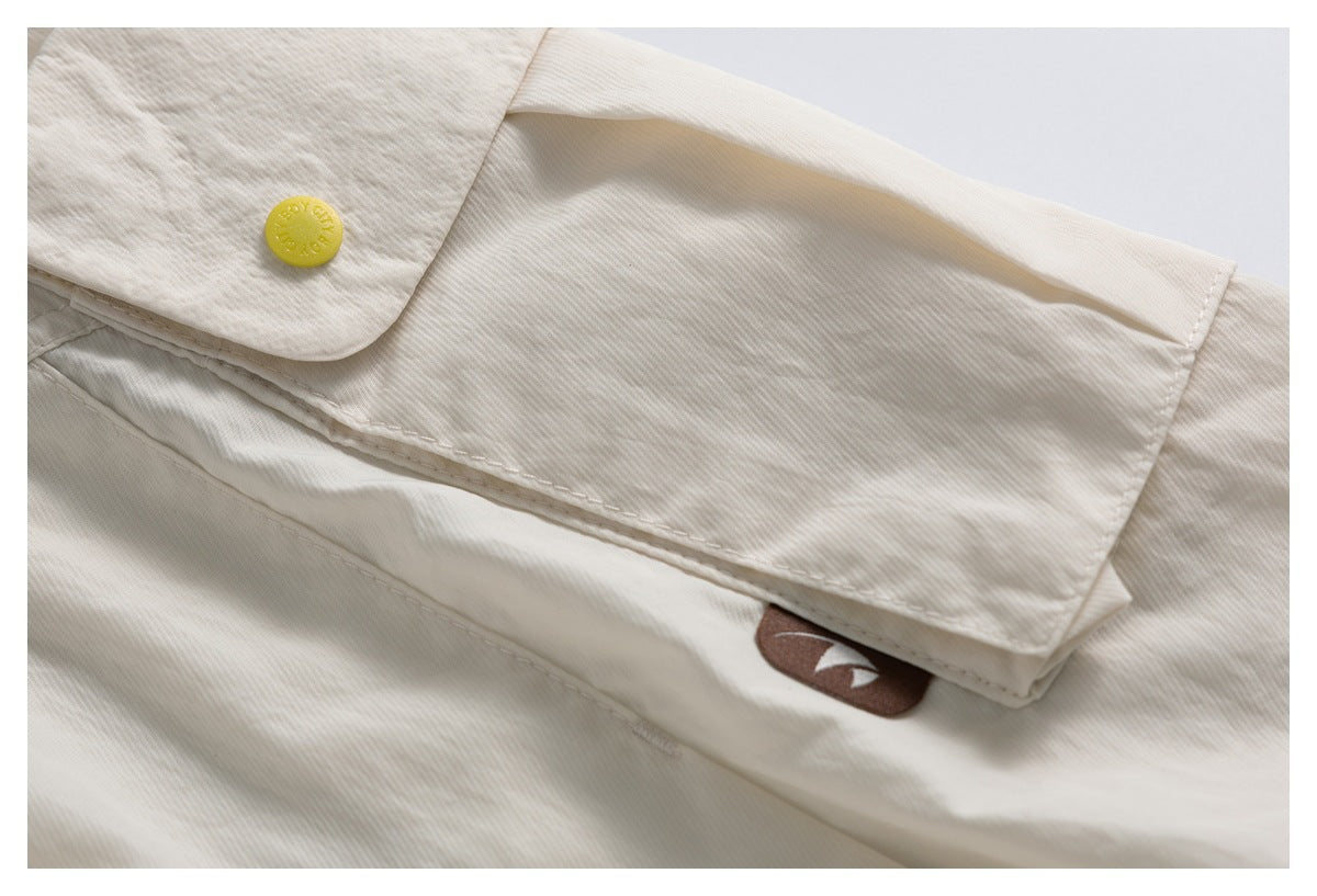 Close-up of an ivory garment flap with a yellow button and a brown fabric logo patch.