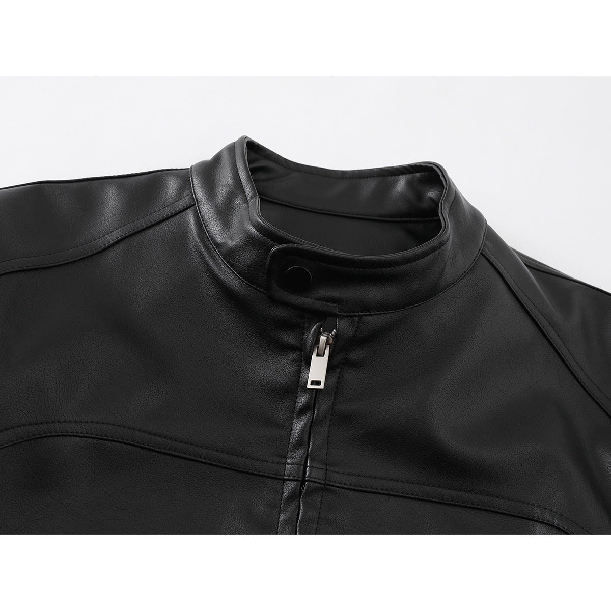 Close-up of a black jacket’s stand collar, snap tab, front zipper, and stitched panels.