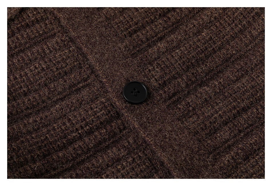 Close-up of a black button on dark brown textured knit fabric.