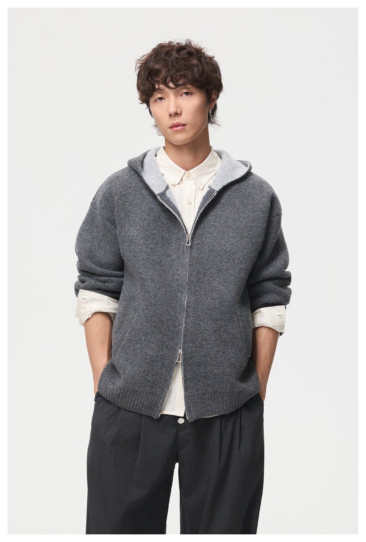 Model wearing a charcoal hooded zip cardigan with a pale contrasting hood lining and rolled sleeves.