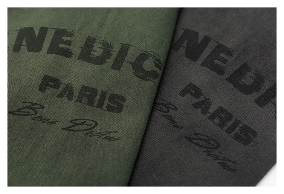 Close-up of black BENEDICTUS PARIS prints on olive green and charcoal jacket fabric.