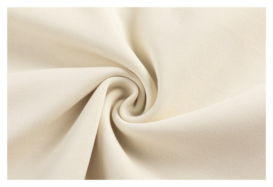 Macro close-up of cream-colored garment fabric gathered into a soft spiral.