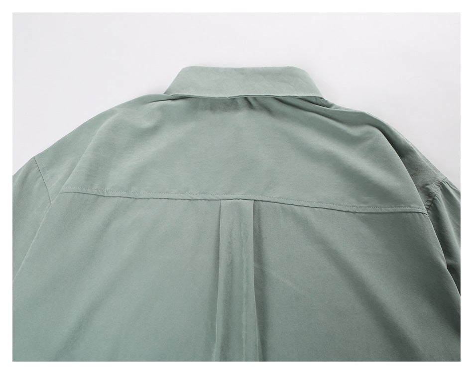 Close-up of a sage green shirt back showing the collar, horizontal yoke seam, and center pleat.