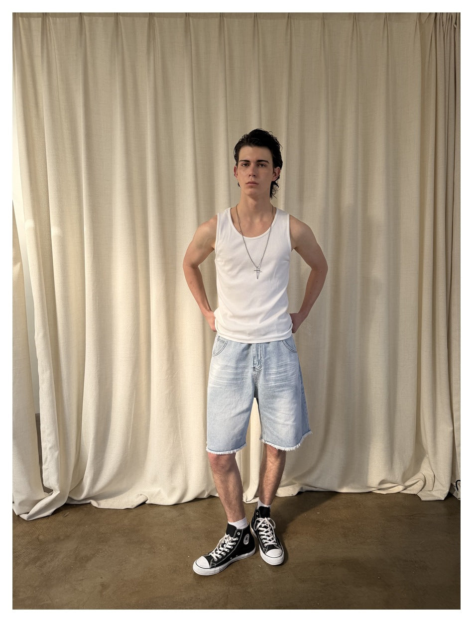 Model wearing a white tank top and light-wash denim shorts with frayed hems.