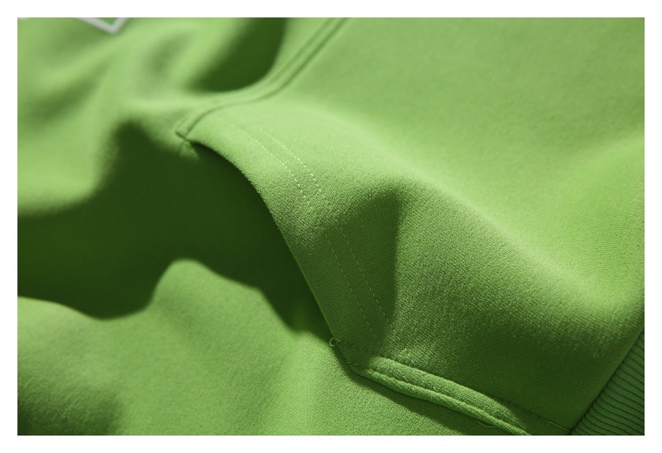 Angled close-up of the green hoodie’s kangaroo pocket stitching and edge.