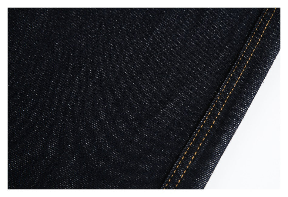 Close-up of dark indigo denim with a double-stitched golden seam along the edge.