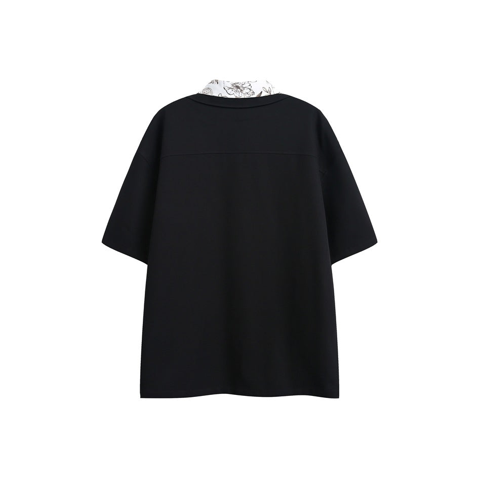 Back view of a black short-sleeve shirt with a light floral collar and a horizontal yoke seam.