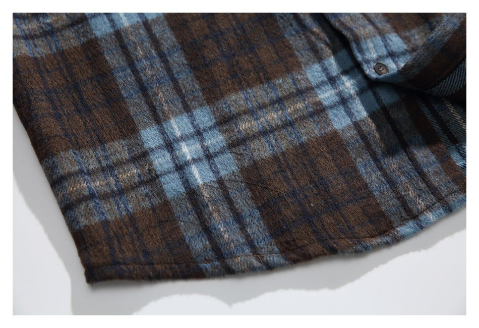 Close-up of the brown and blue plaid shirt's stitched lower hem and folded fabric.