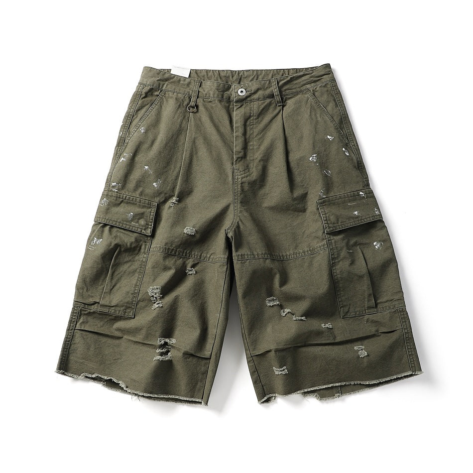 Army green cargo shorts, front flat lay, with distressed holes, paint splatters, flap pockets and a raw frayed hem